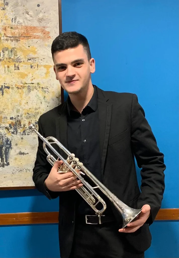 Xabi, profesor de trompeta, con una trompeta en la mano y sonriente